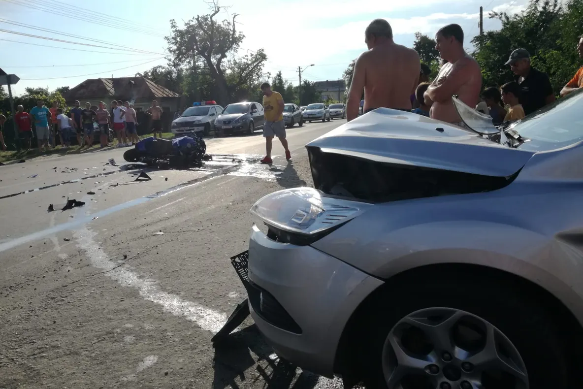 Motociclistul grăbit s-a lovit de-o remorcă și a urcat pe o mașină! Două persoane rănite!